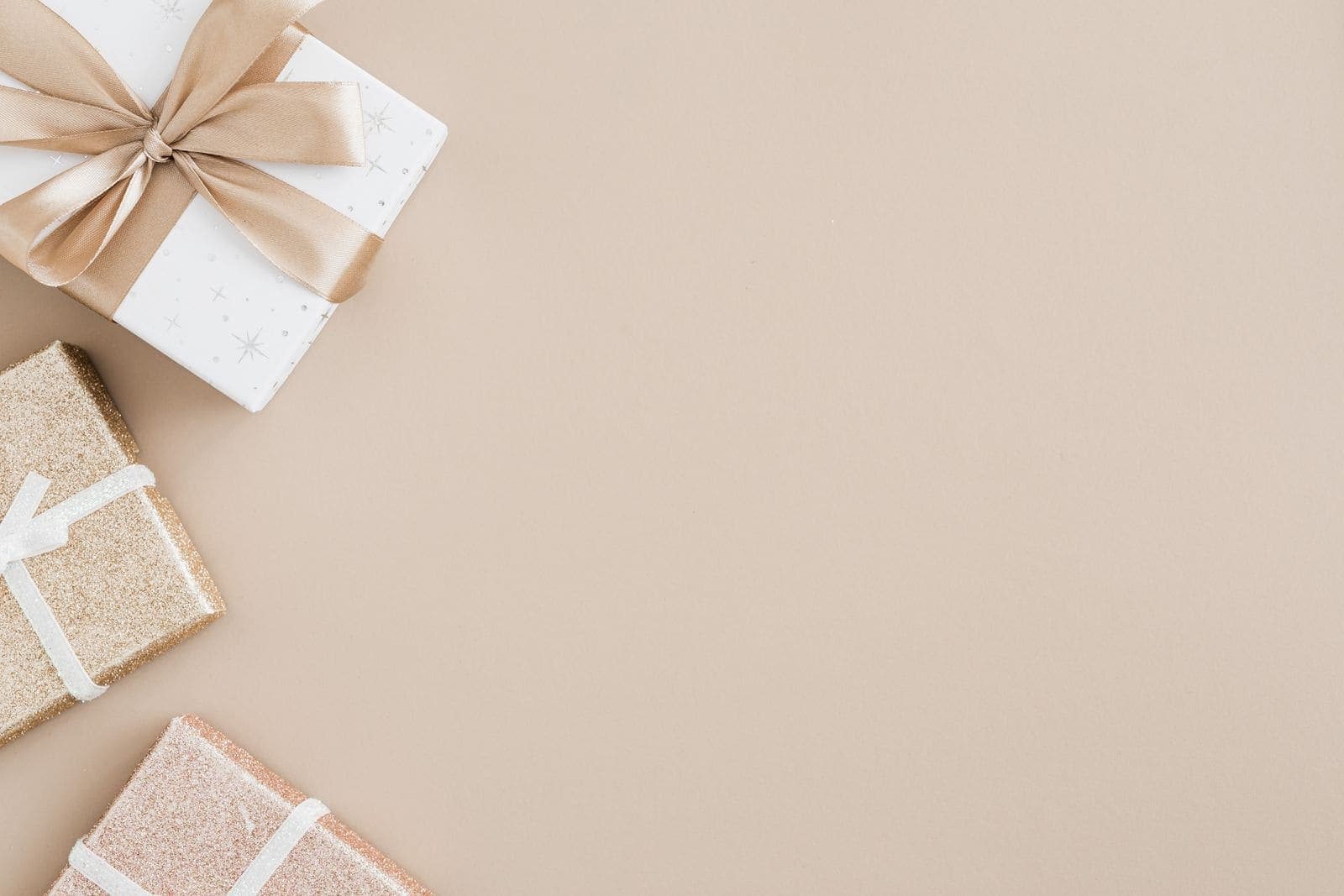 Wrapped gift boxes with ribbons laid out on a plain beige background